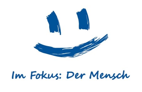 Das Bild zeigt ein Logo mit einem lachenden Gesicht und dem Titel 