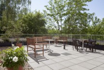 Terrasse der Station P1 mit gemütlichen Sitzgelegenheiten, Pflanzen und einem großen Baum im Hintergrund