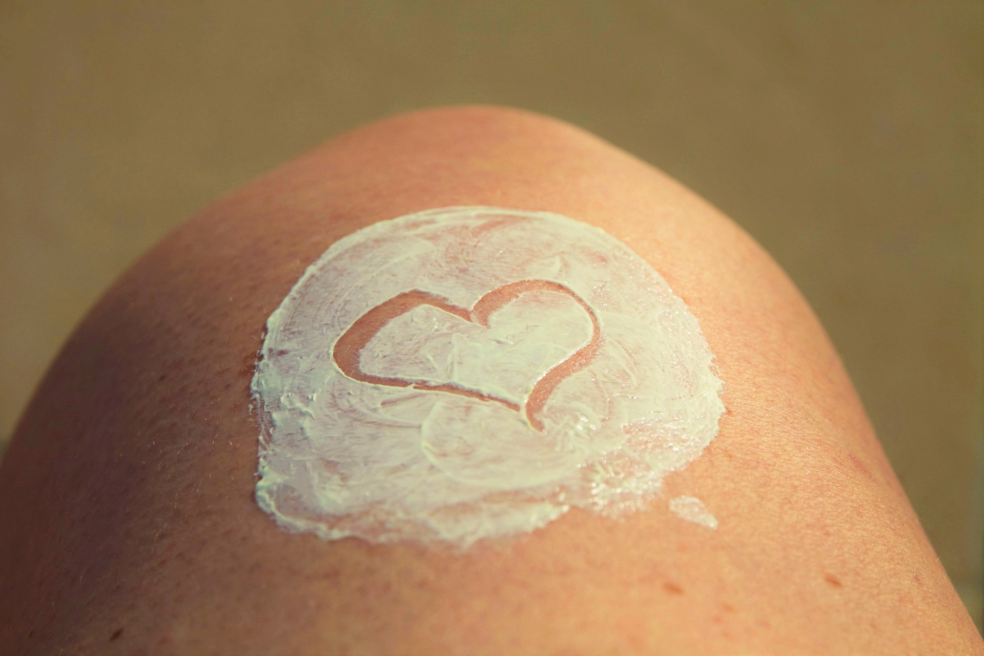 Bild zeigt ein Knie mit Salbe in das Herz gezeichnet ist.